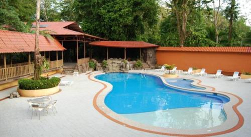 una piscina en un patio con sillas y un edificio en Hotel El Bambu, en Sarapiquí