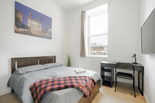 a bedroom with a bed and a desk and a window at HoMa Homestay Hotel by Olympic Stadium Montreal Auberge-Hostel in Montréal