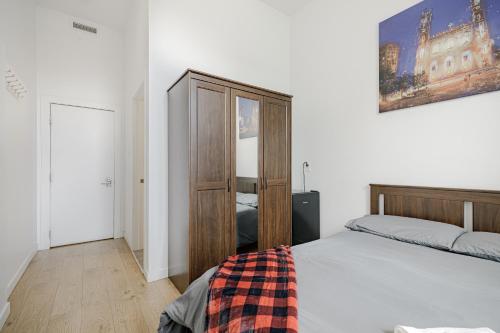 a bedroom with a bed and a wooden cabinet at HoMa Homestay Hotel by Olympic Stadium Montreal Auberge-Hostel in Montréal