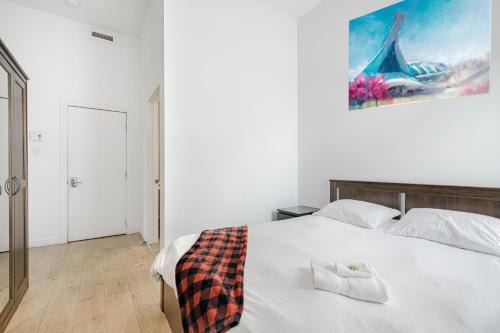 a bedroom with a white bed with a picture on the wall at HoMa Homestay Hotel by Olympic Stadium Montreal Auberge-Hostel in Montréal