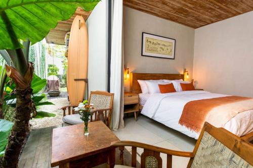 a bedroom with a bed and a table and a surfboard at OLA HOUSE Private 2 BR with Salt Pool in Uluwatu in Uluwatu