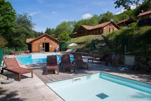 - une piscine avec un groupe de chaises à côté d'une maison dans l'établissement Les Châtaigniers du Lac, à Pourcharesses