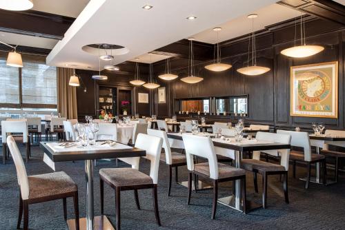 a dining room with tables and chairs and lights at Hôtel Diana Restaurant & Spa by HappyCulture in Molsheim