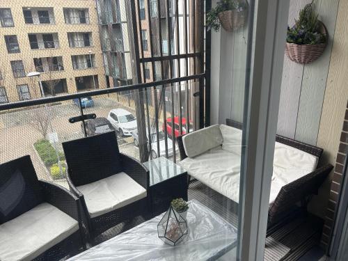 a balcony with two chairs and a bed and a window at Immaculate 2-Bed Apartment in Romford in Romford