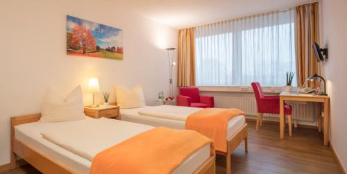 a hotel room with two beds and a desk at Heinrich Pesch Hotel in Ludwigshafen am Rhein