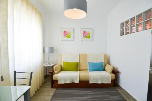 a living room with a couch with colorful pillows at Holidays Nazaré Centro in Nazaré