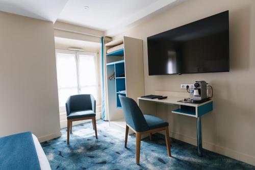 um quarto com uma secretária, 2 cadeiras e uma televisão em Hotel Des Remparts Perrache em Lyon