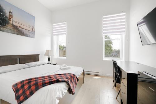 a bedroom with a bed and a desk and two windows at HoMa Homestay Hotel by Olympic Stadium Montreal Auberge-Hostel in Montréal
