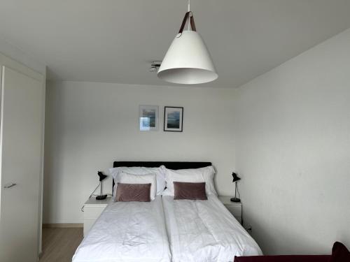 Dormitorio blanco con cama y pared blanca en Room with 360° view overlooking Lake Geneva and Alps, en Puidoux