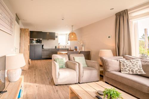 Il comprend un salon avec un canapé et des chaises ainsi qu'une cuisine. dans l'établissement Appartementencomplex Juliana 34, à De Koog