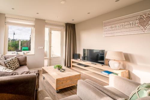- un salon avec un canapé et une télévision dans l'établissement Appartementencomplex Juliana 34, à De Koog