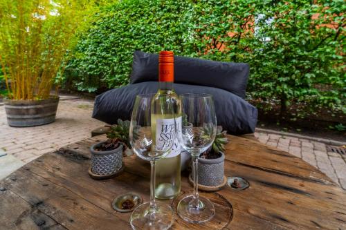 a bottle of wine and two wine glasses on a wooden table at Auszeit Hotel Hamburg in Hamburg
