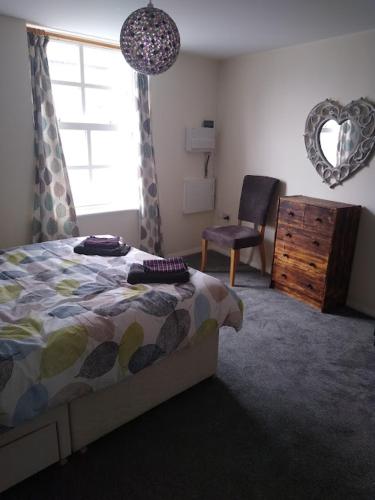a bedroom with a bed and a chair and a window at 124A Castle Street Hinckley in Hinckley