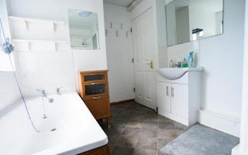 a bathroom with a sink and a tub and a mirror at Charming 6-Bed House in Reading in Reading