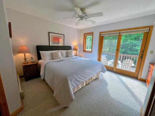 a bedroom with a bed with a ceiling fan and a balcony at FC54 large mountain cottage with views in Bretton Woods