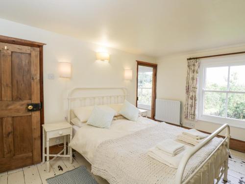 a white bedroom with a bed and a window at Fourways in Pewsey
