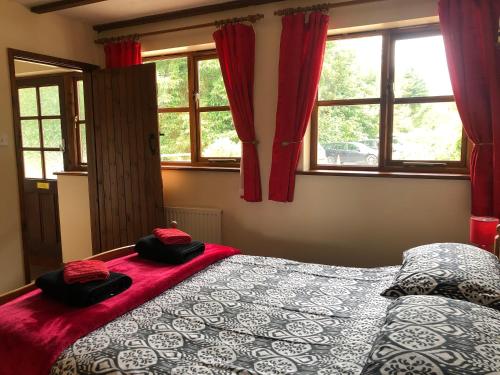 Schlafzimmer mit einem Bett und Fenstern mit roten Vorhängen in der Unterkunft Deanwood Holiday Cottages in Yorkley