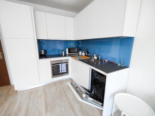 a small kitchen with white cabinets and blue walls at Brissaghino al Lago 5* in Brissago