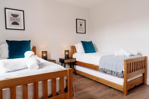 two beds in a room with blue pillows at Sawley Cottage in Skipton