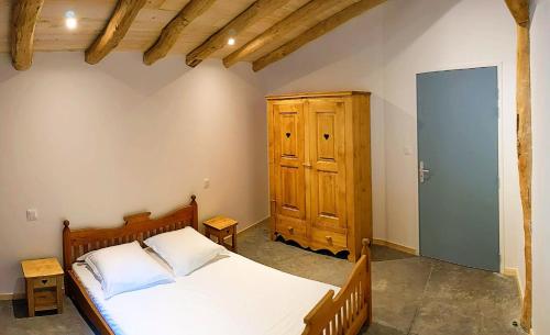 une chambre avec un lit et une armoire en bois dans l'établissement Gite du Moulin, à Sainte-Marguerite-Lafigère