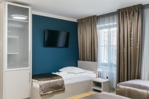 a hotel room with a bed and a tv on the wall at NOZON Apartments & Wellness in Odorheiu Secuiesc