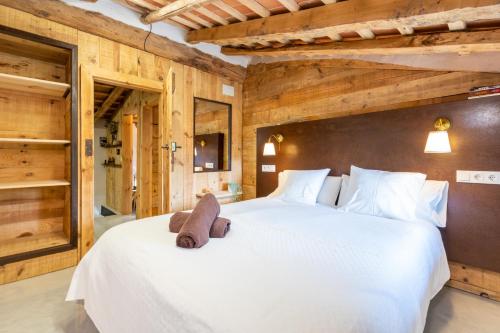 a bedroom with two large white beds with wooden walls at El Roure in Molló