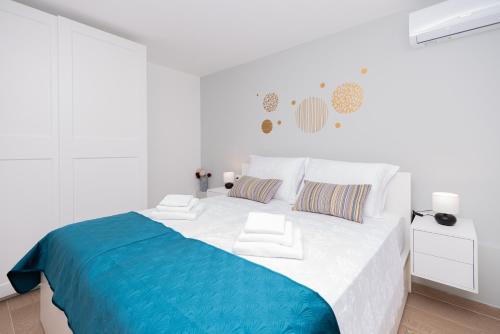 a white bedroom with a large bed with a blue blanket at Apartment Emmi in Omiš