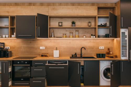 a kitchen with black cabinets and a washer and dryer at NOZON Apartments & Wellness in Odorheiu Secuiesc