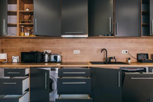 a kitchen with black cabinets and a sink at NOZON Apartments & Wellness in Odorheiu Secuiesc