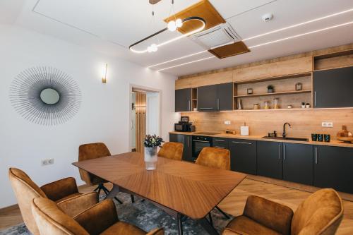 a kitchen and dining room with a wooden table and chairs at NOZON Apartments & Wellness in Odorheiu Secuiesc