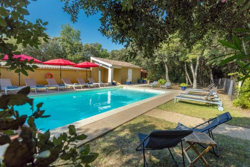 - une piscine avec des chaises et une maison dans l'établissement Logis La Bastide De Grignan Hotel & Restaurant "La Chênaie", à Grignan