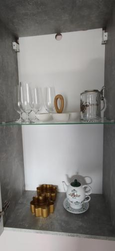 a shelf with glasses and a tea set on it at Veronika's House je prijeten, miren apartma v naravi, blizu mesta in Celje