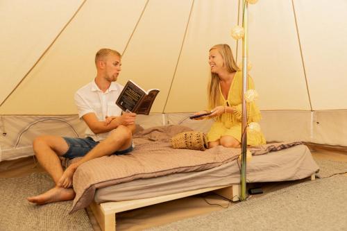a man and woman sitting on a bed in a tent at Niiduveere glämping in Viru-Nigula