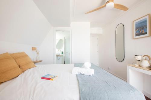 a white bedroom with a bed and a ceiling fan at Far Out Inn in Donostia-San Sebastián