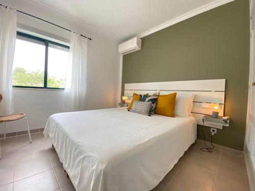 sypialnia z dużym białym łóżkiem z żółtymi poduszkami w obiekcie Apartamento Amparo-T2 c/piscina w mieście Carvoeiro