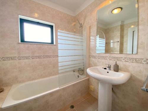 La salle de bains est pourvue d'un lavabo, d'une douche, d'une baignoire et d'un lavabo blanc. dans l'établissement Apartamento Amparo-T2 c/piscina, à Carvoeiro