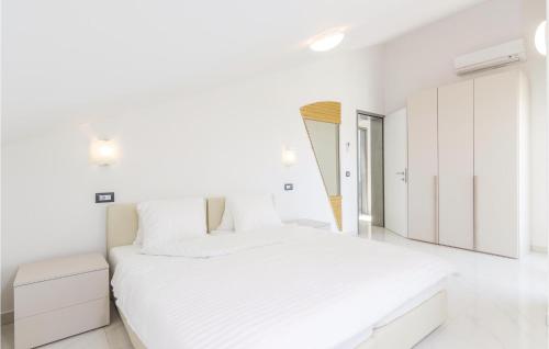 ein weißes Schlafzimmer mit einem großen Bett und weißen Schränken in der Unterkunft Beautiful Apartment In Funtana With Wifi in Funtana