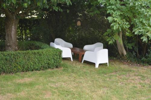 three white chairs and a wooden table in the grass at Au Bonheur d'Aimée à 14 min de Pairi Daiza in Montignies-lez-Lens