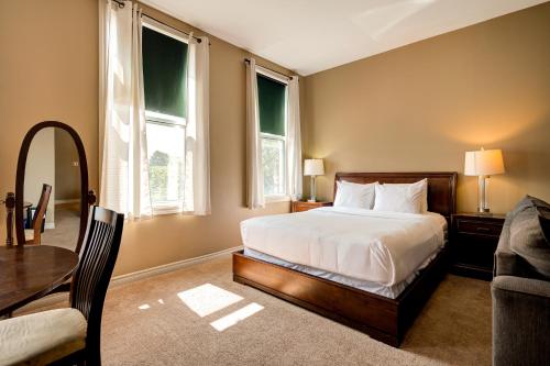 a bedroom with a bed and a table and two windows at Wellington Street Inn by Hoco Hotels Collection in Stratford
