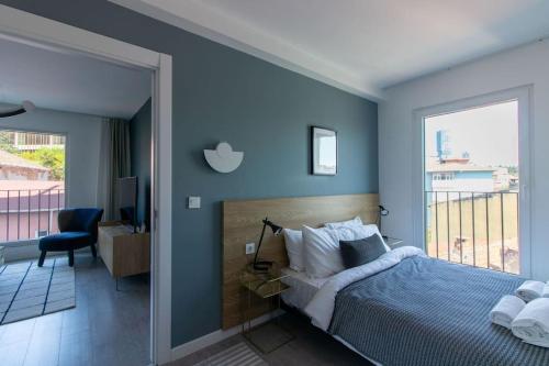 een blauwe slaapkamer met een bed en een groot raam bij Warm Bright 2BR Urban Home w/ Free Shuttle+Parking #127 in Istanbul