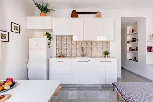 a kitchen with white cabinets and a bowl of fruit on a table at One bedroom Machane Yehuda Design Apartment in Jerusalem
