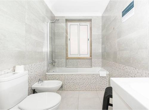 a white bathroom with a toilet and a bath tub at HOUZE_4 room flat in Central Lisbon near Zoo in Lisbon
