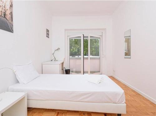 una camera bianca con un letto e una finestra di HOUZE_4 room flat in Central Lisbon near Zoo a Lisbona