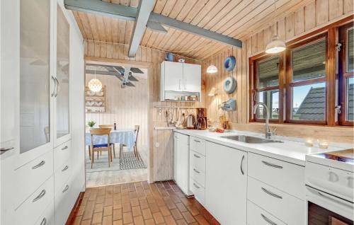 eine Küche mit weißen Schränken und einem Tisch in der Unterkunft Kivi in Fanø