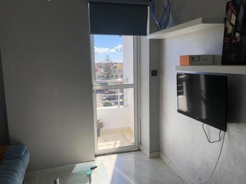 a living room with a television and a large window at Logement entier : appartement in Larache