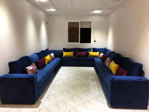 a living room with a blue couch with colorful pillows at Logement entier : appartement in Larache