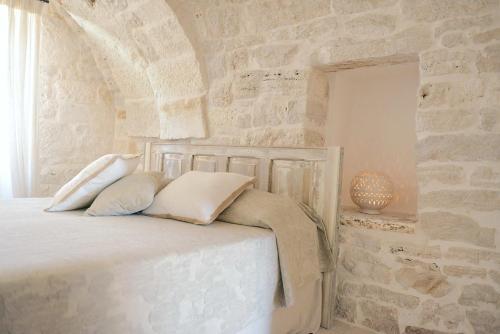 - une chambre avec un mur en pierre et un lit avec des oreillers dans l'établissement Masseria Signora, à Martina Franca