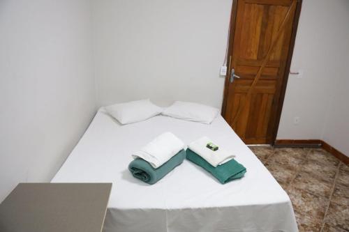 Una cama blanca con dos toallas encima. en Pousada dos Ventos Refugio Urbano en Cuiabá