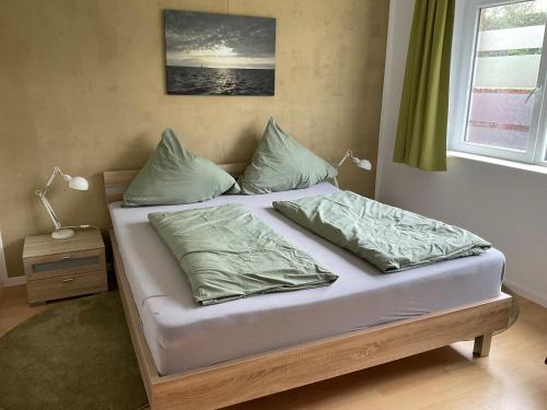 a bed with green sheets and pillows in a bedroom at Ferienwohnung Bunte Kuh Wangerooge in Wangerooge