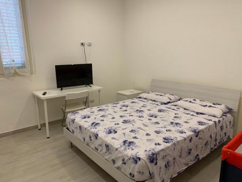a bedroom with a bed and a desk with a television at KIKA HOUSE in Cagliari